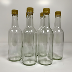 Six empty clear glass bottles with gold screw caps.
