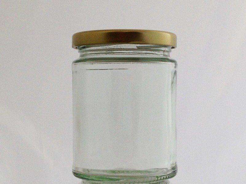 Single empty clear glass jam jar with a gold-coloured twist-off lid
