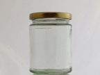 Single empty clear glass jam jar with a gold-coloured twist-off lid