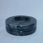 Dark circular marble holder with pale mottling and a recessed centre, shown empty