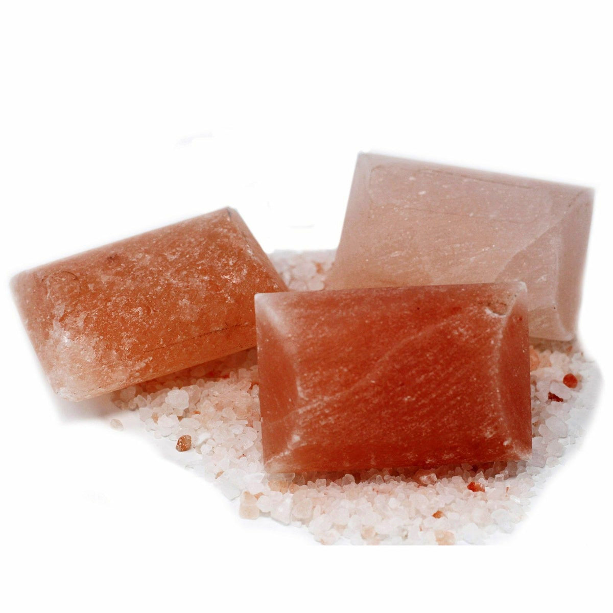 Three rectangular pink Himalayan salt bars arranged on coarse salt crystals