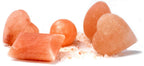 Pink Himalayan salt stones in heart, ball, egg and rectangular shapes arranged on coarse salt